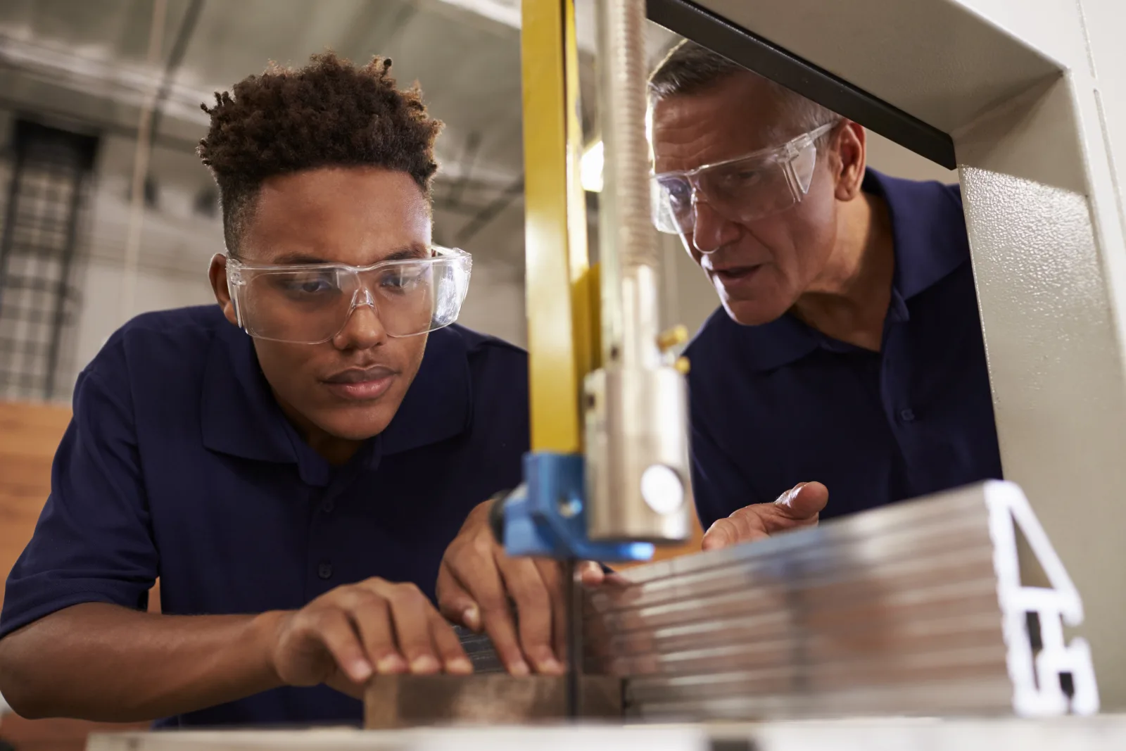 A student in safety glasses working with a CTE mentor in a shop class