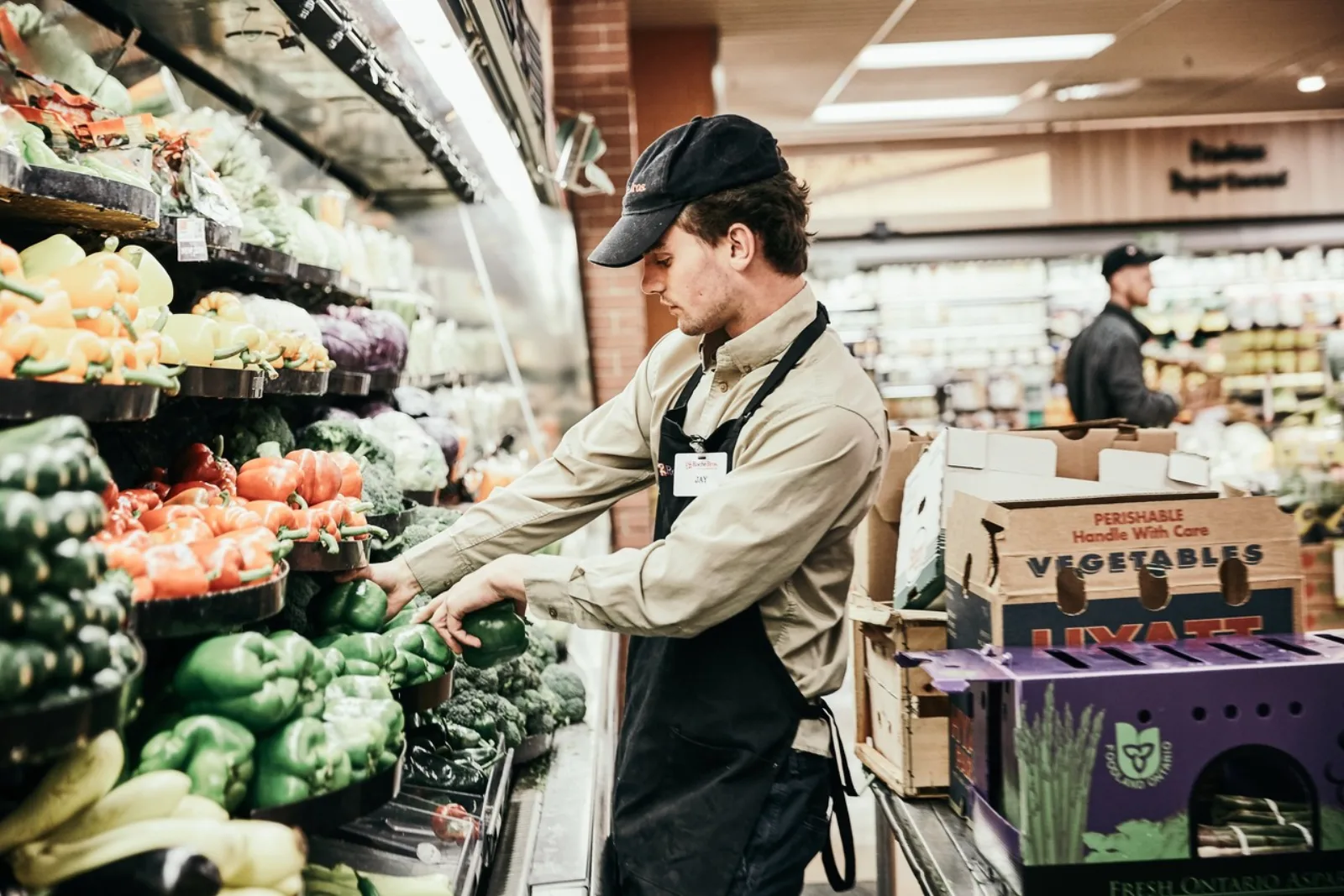 A young person working in a grocery produce section